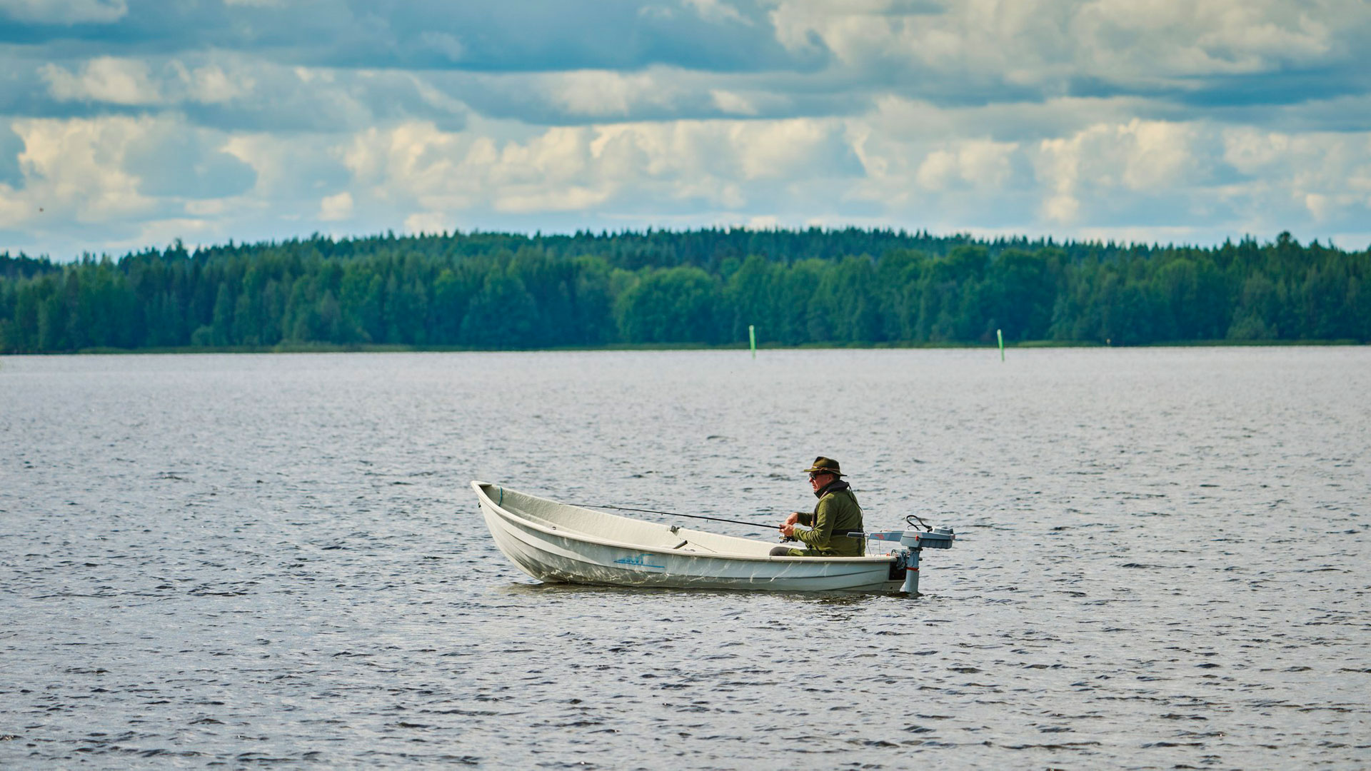 Mies kalastaa veneestä järvellä.
