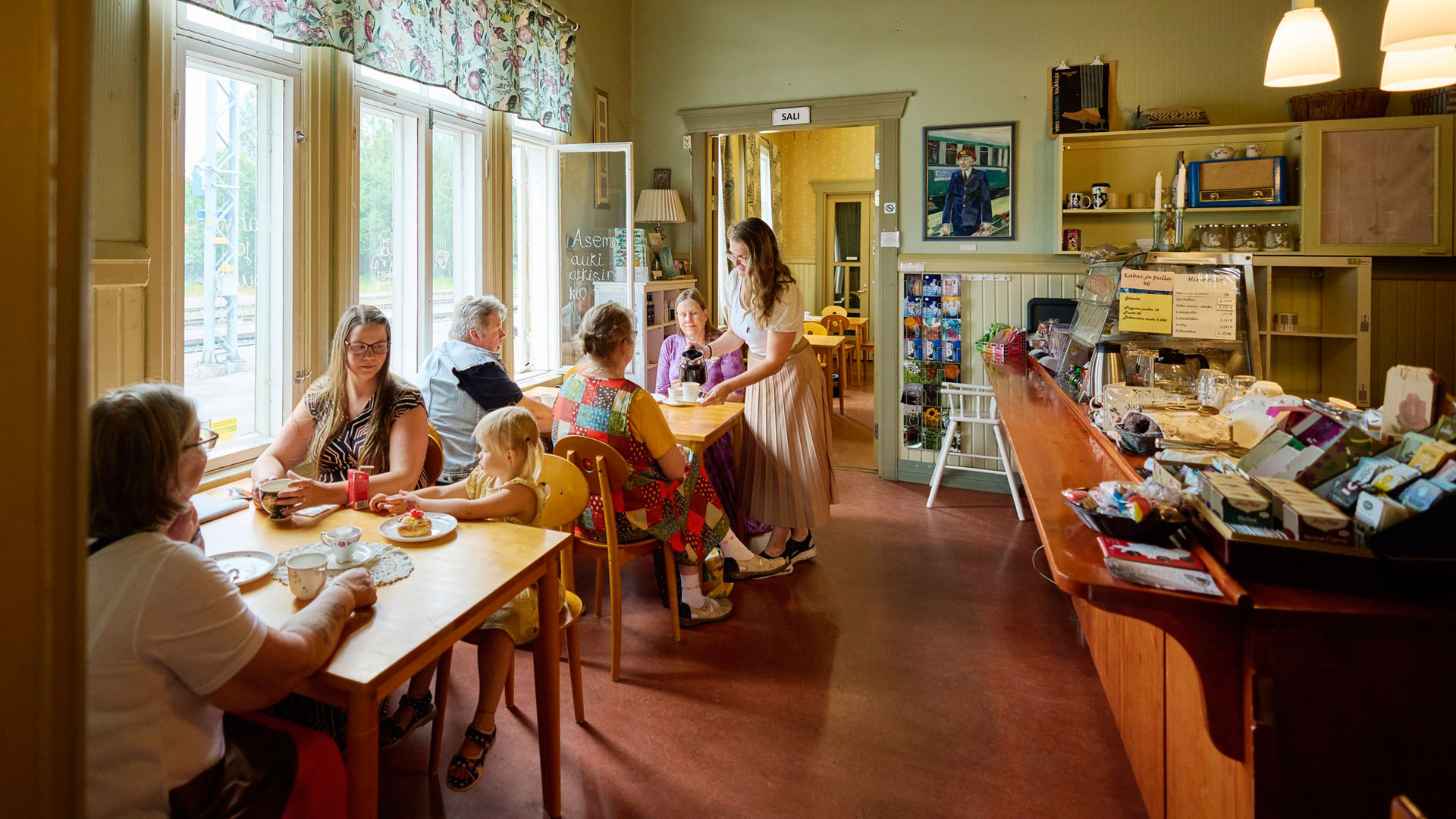 Ihmisiä istuu kahvion pöydissä.