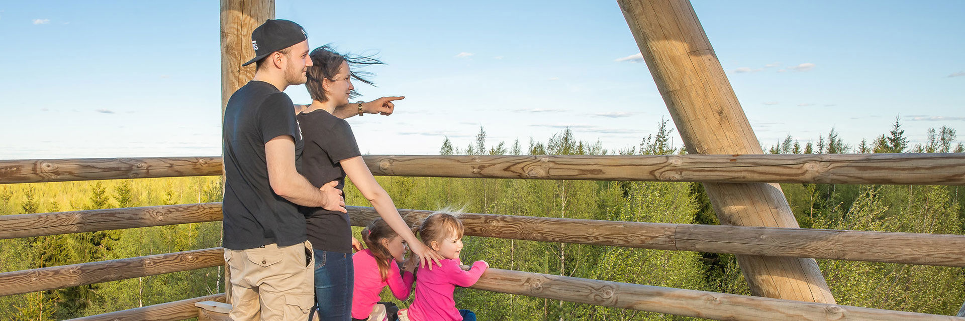 Mies, nainen ja kaksi pikkutyttöä seisovat puisen näkötornin huipulla ja katselevat maisemia.